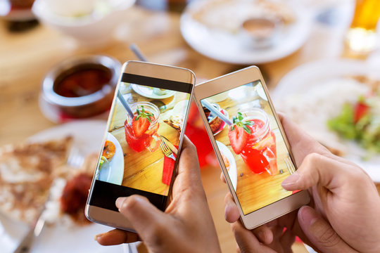 hands with drinks on smartphones at restaurant