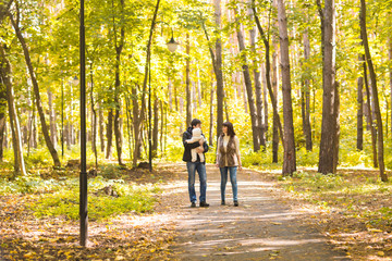 Obraz premium Happy young family in the autumn park outdoors on a sunny day. Mother, father and their little baby boy are walking in the park. Love, family and parenthood concept.