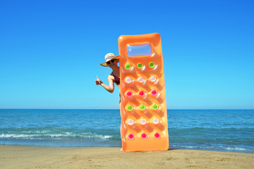 Caucasian girl with hat and inflatable mattress on the beach. Summer vacation by the sea.