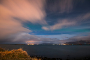 Beautiful night sky sea view with a mountains on the background and a little bit of aurora borealis