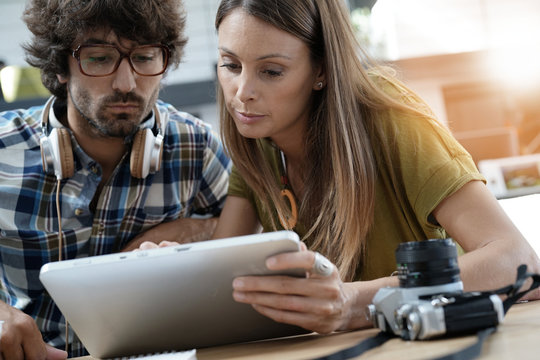 Trendy people in office lounge websurfing on tablet