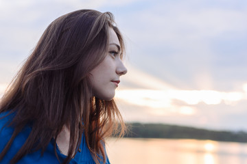 summer vacation happy portrait beautiful woman girl caucasian asian blended in blue shirt posing on background sky lake water sunset long hair brunette outdoors