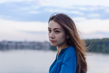 Summer happy portrait beautiful woman girl caucasian asian blended in blue shirt posing on background sky lake water sunset long hair brunette outdoors