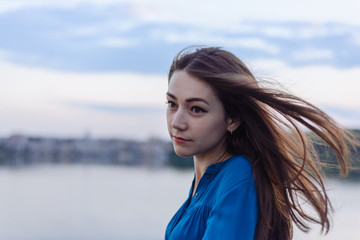 Summer happy portrait beautiful woman girl caucasian asian blended in blue shirt posing on background sky lake water sunset long hair brunette outdoors