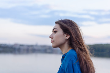 Summer happy portrait beautiful woman girl caucasian asian blended in blue shirt posing on background sky lake water sunset long hair brunette outdoors