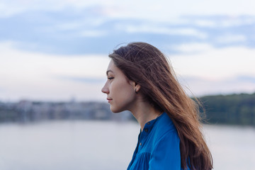 Summer happy portrait beautiful woman girl caucasian asian blended in blue shirt posing on background sky lake water sunset long hair brunette outdoors