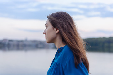 Summer happy portrait beautiful woman girl caucasian asian blended in blue shirt posing on background sky lake water sunset long hair brunette outdoors