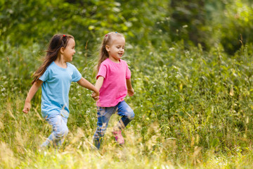 Obraz premium Two little girls running around holding hands in the park