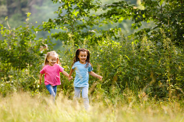 Two little girls running around holding hands