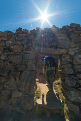 Tourist exploring the ancient mysterious Inca labyrinth-like settlement, called Chinkana, on the Island of the Sun, Titicaca Lake, Bolivia. Concept of travel adventures in the Americas.