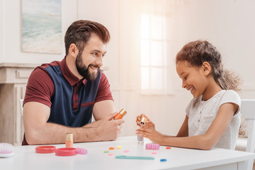 Happy multiethnic father and daughter painting nails together at home