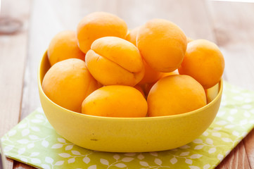 Heap of apricots in wooden bowl on table