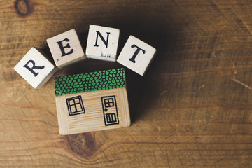 Home rent concept. House model with rent word made from wooden blocks.
