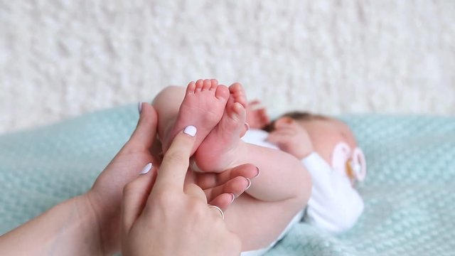 Mothers hands holding legs of newborn baby girl.