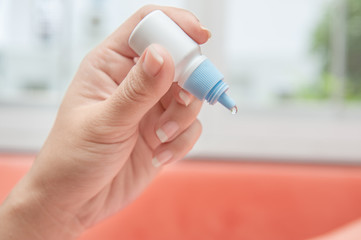 Hand with eye drop bottle