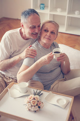 Older couple having breakfast  on bed.