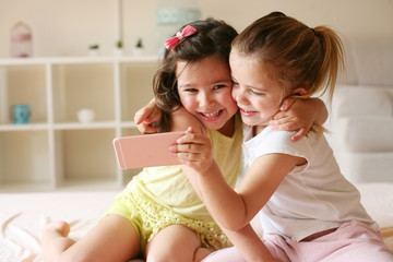 Two little girls sitting on bed together.