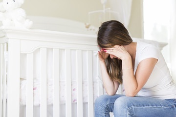 Depressed young woman in baby room