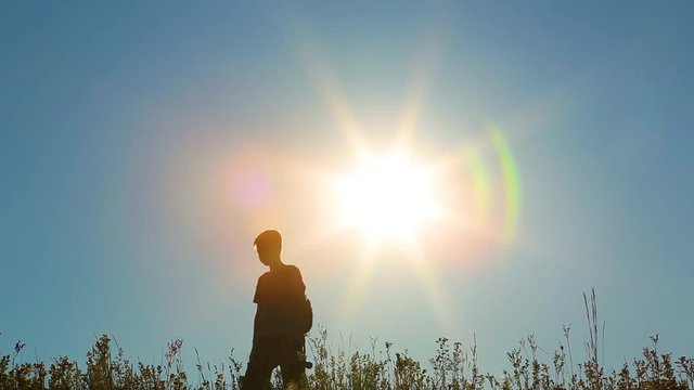 Silhouette of little kid uses old retro movie camera for shooting his daddy in beautiful sunset landscape for family video album. Happy family has fun on vacations outside.