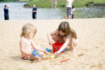 Zwei Mädchen spielen mit Sandspielzeug im Sand