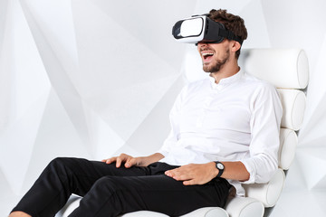 Excited young man is getting experience using VR-headset glasses of virtual reality gesticulating...