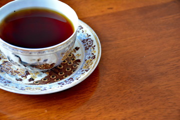Cup of black tea on wooden table