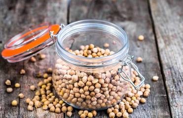 Raw chickpeas in rustic jar on wooden table, healthy vegan cooking ingredients