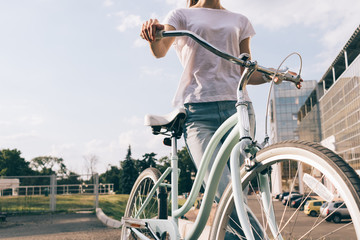 Cropped image of a young woman in jeans and a T-shirt with a bicycle