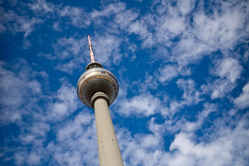The TV tower on the Alexanderplatz in Berlin with blue sky and white clouds in the background.