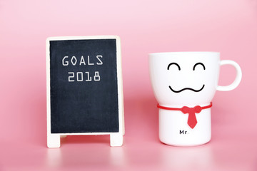 GOALS 2018 text on blackboard and Coffee cup smiling