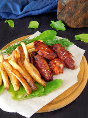 French fries and grilled chicken wings on the green salad