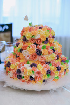 Beautiful white and colored wedding cake. A bride and a groom is cutting their wedding cake