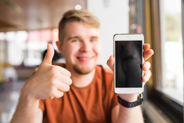 Happy casual man showing blank smartphone screen and thumb up