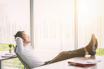 Businessman relaxing concept: businessman sitting with feet up at office desk