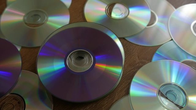 Optical Discs falling onto big pile of DVDs or CDs. Slow motion.