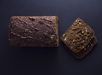 Danish rye bread made from sour dough with whole grain flour and seeds. Sliced and isolated on black background