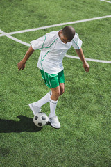 african american soccer player training with ball on soccer pitch © LIGHTFIELD STUDIOS
