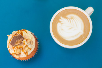 Caramel nut cupcake and cup of coffee on table. Top view.