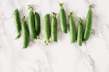 Green peas on the white marble table. Summer background. Concept of vegetarian food