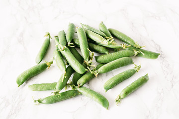 Green peas on the white marble table. Summer background. Concept of vegetarian food