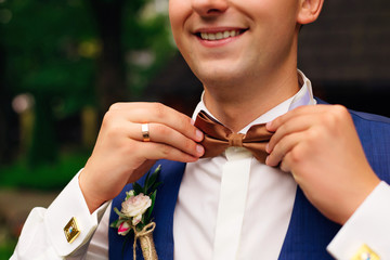 Closeup of adult handsome man adjusting stylish brown male bow t