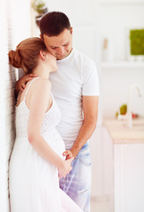 young pregnant couple in love, hugging at home