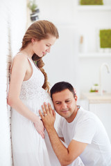 happy future daddy listen to heartbeat in pregnant belly