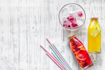 Bottle with fresh lemonade and ice cube on wooden background top view copyspace