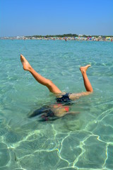 A young girl swims in apnea in the crystal clear sea.