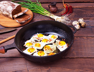 Fried quail eggs in a black cast-iron frying pan