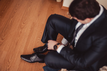 The man wears shoes. Tie the laces on the shoes. Men's style. Professions. To prepare for work, to the meeting.