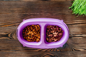 Obraz na płótnie Canvas Cat feed in bowl and grass on wooden background top view copyspace