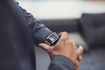 A man putting on watch. The bridegroom at the wedding with the clock