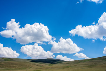 shadows of fluffy clouds over green hills at sunny day  

